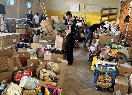 Grafika 9: Wolontariusze pomagają segregować i pakować dary dla powodzian.