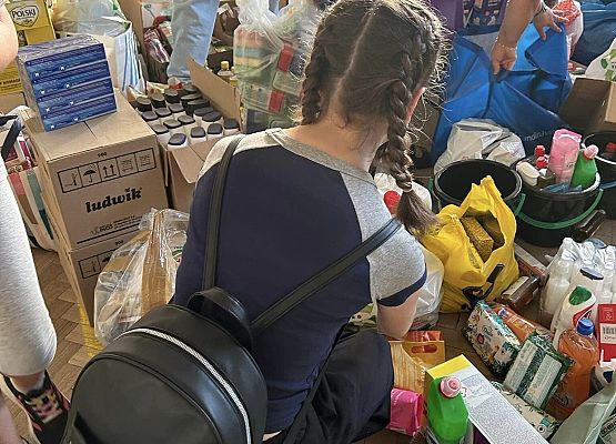 Grafika 12: Wolontariusze pomagają segregować i pakować dary dla powodzian.